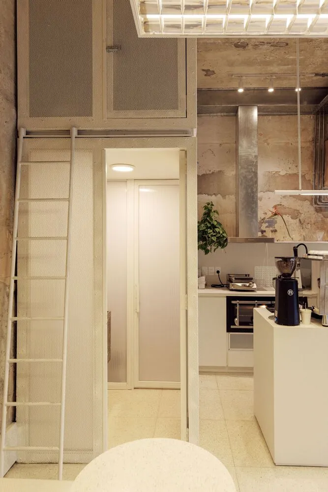 Open kitchen and bathroom area with white cabinets, a shower stall, potted plants, and a microwave