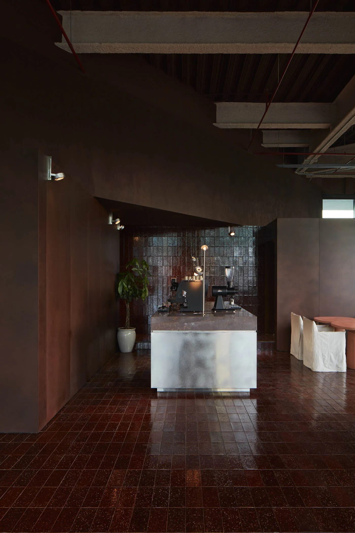 Cozy coffee shop interior with a counter, dining table, potted plants, and a microwave, creating a warm and inviting atmosphere
