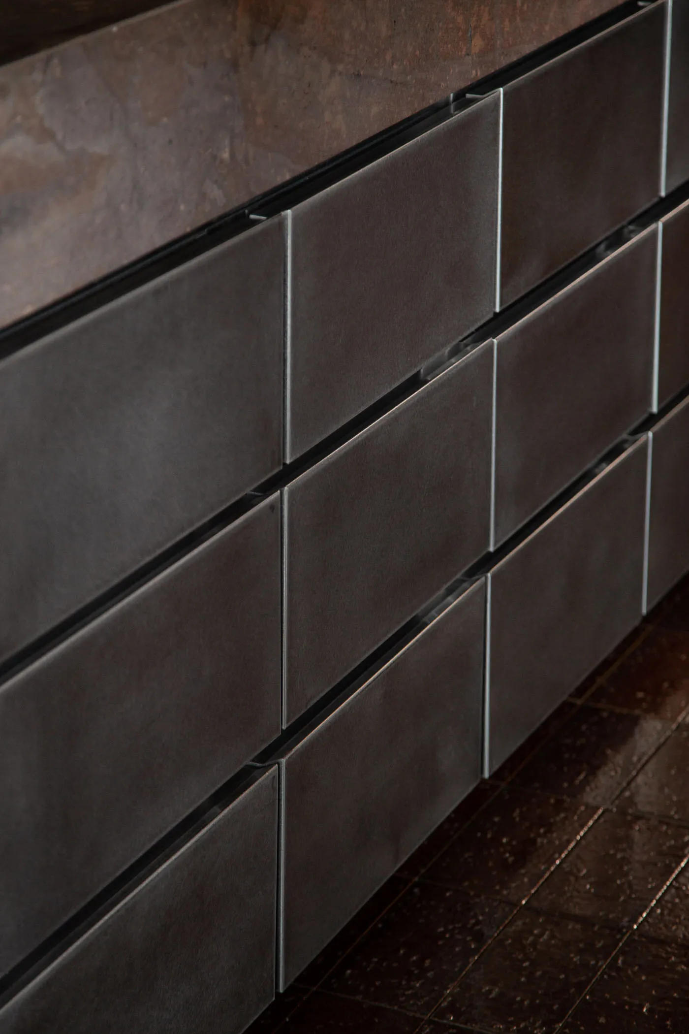 A modern kitchen cabinet with black metal doors and a sleek design, made of stainless steel, with a clean and organized appearance