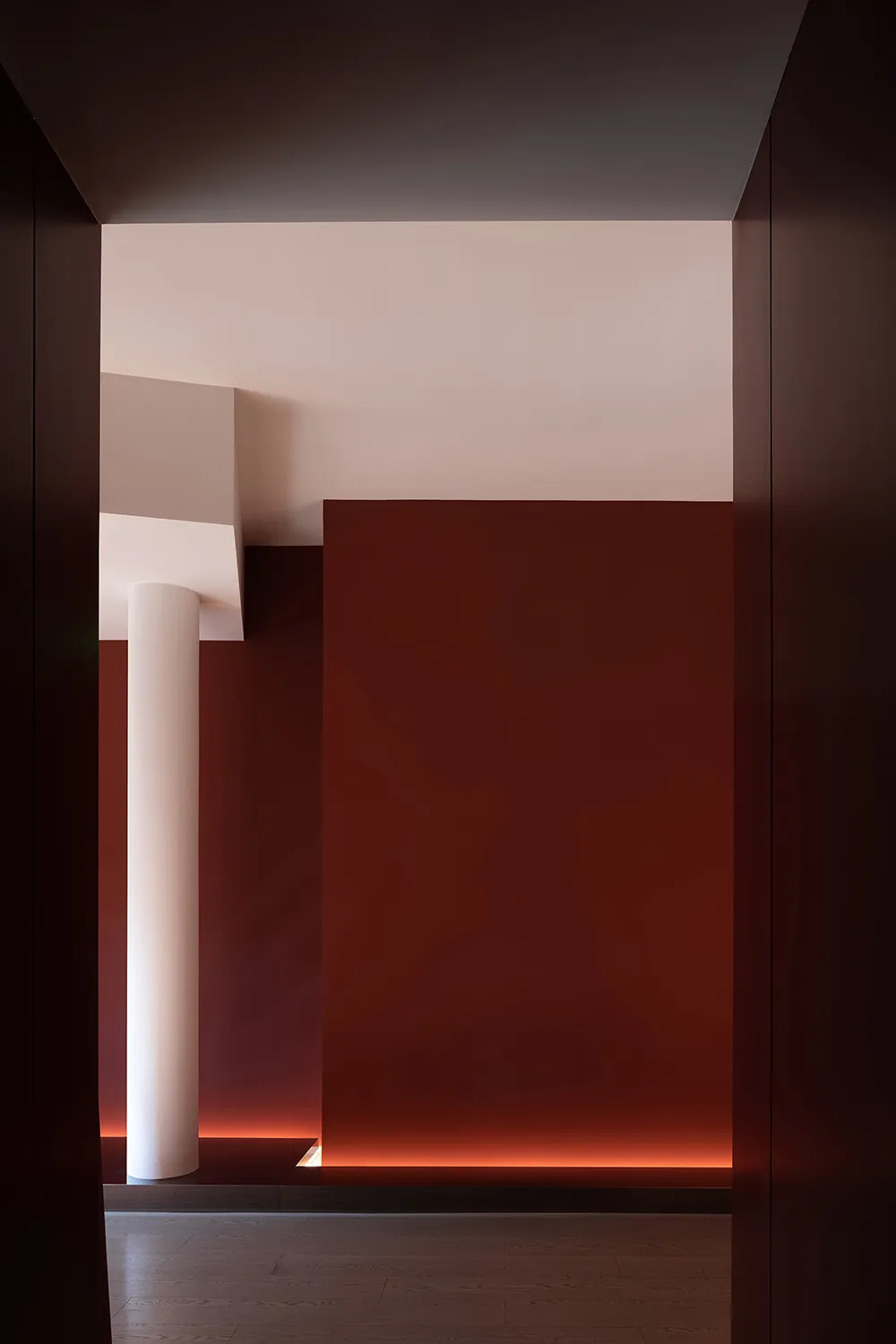 Narrow hallway with red walls and white columns, giving a dark and empty atmosphere