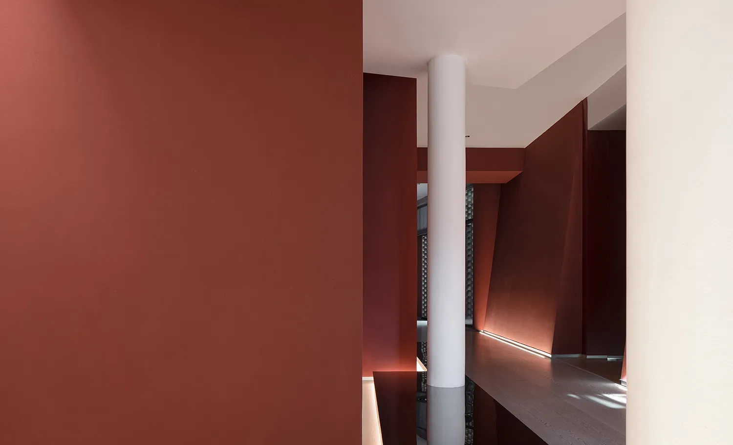 Narrow modern hallway with red walls, a white pillar, and natural light from a window