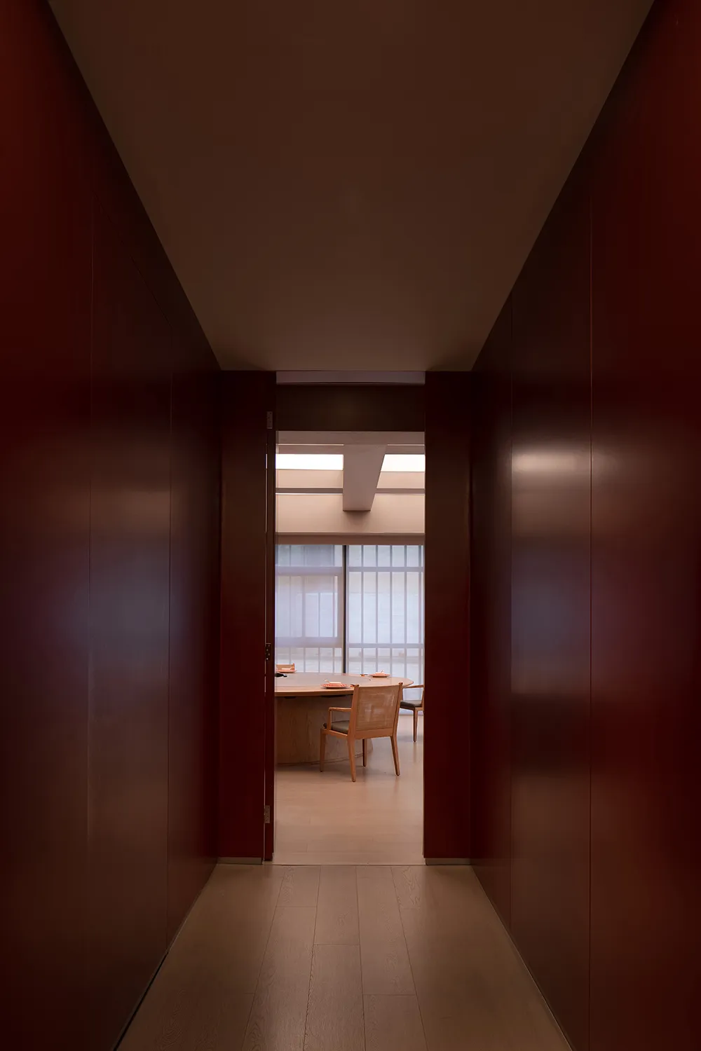 A modern office with a wooden desk and two chairs, surrounded by red panelled walls and well-lit by natural light