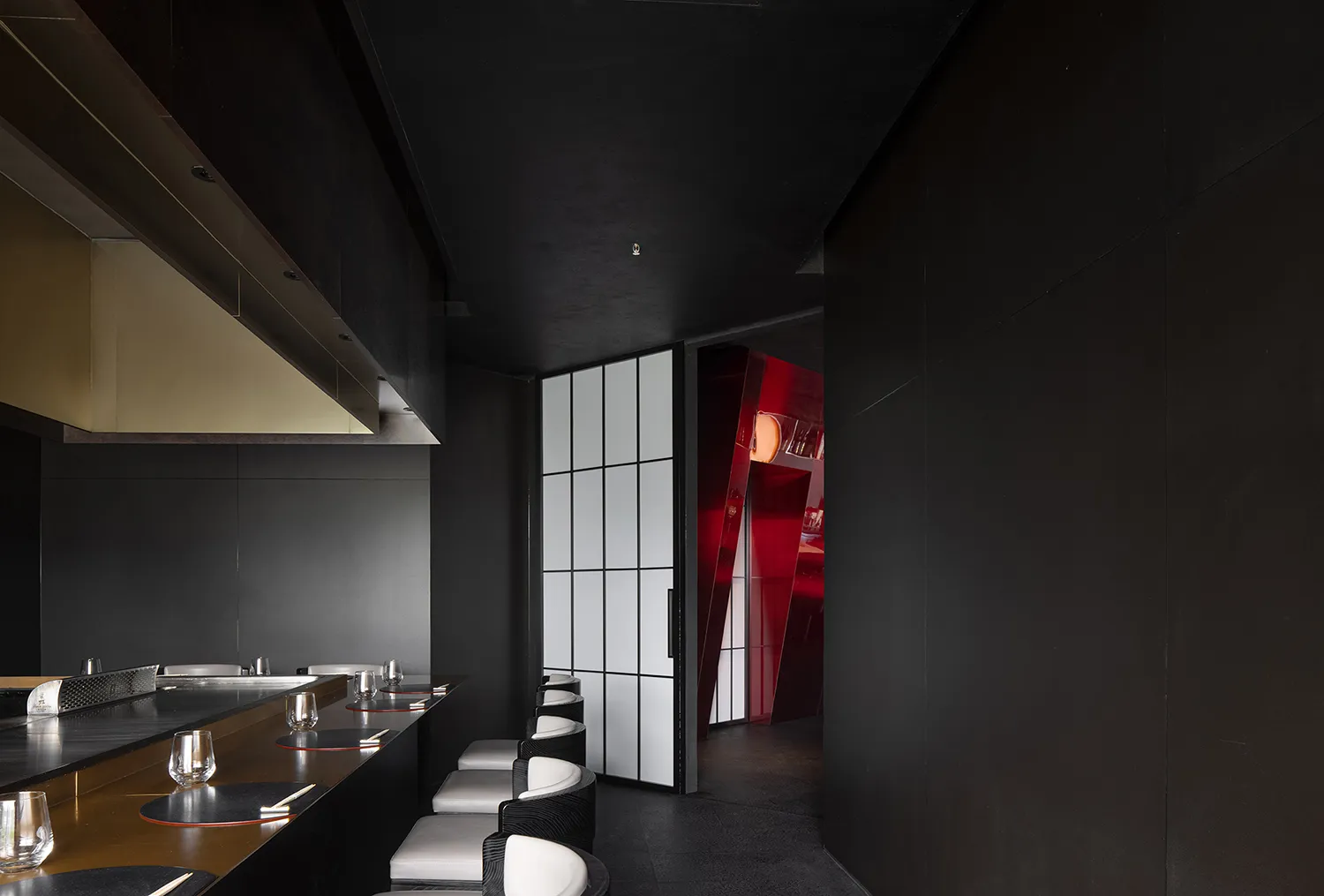 Empty restaurant interior with black walls, red doorway, and chairs placed around the dining area