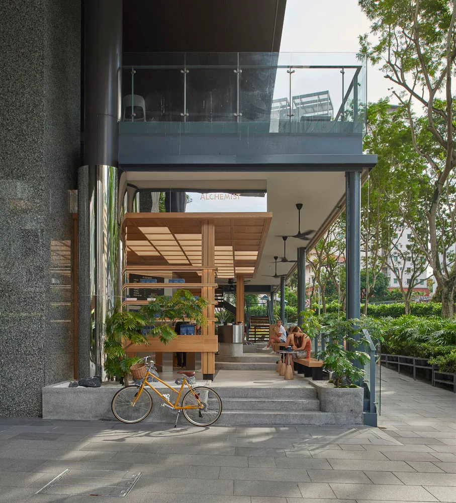 Modern interior space with a large glass wall, wooden frame, potted plants, and two chairs, featuring a contemporary design with natural elements