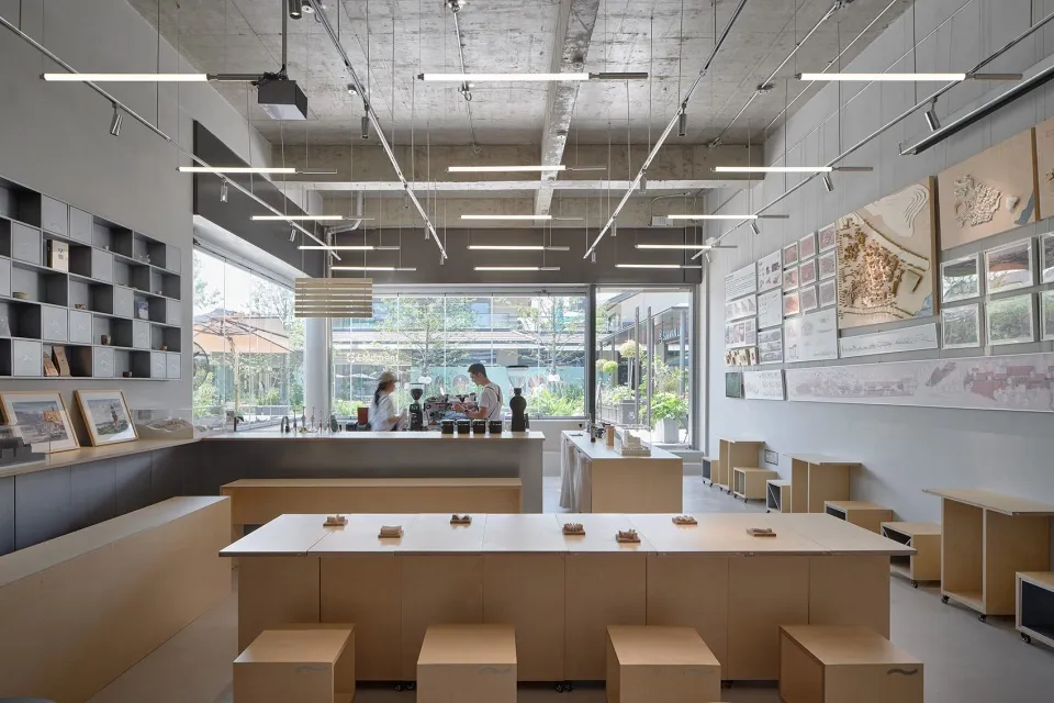 Casual restaurant interior with wooden tables and benches, multiple people sitting and standing, and a focus on socializing and enjoying food together