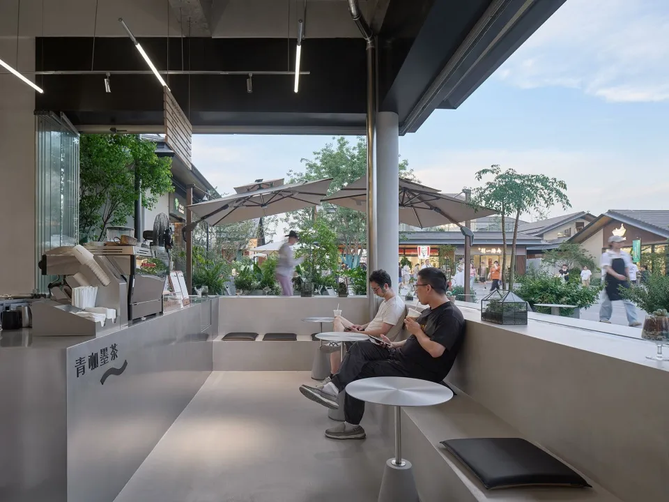 A well-lit indoor space with people sitting on benches and chairs, surrounded by a relaxed and comfortable atmosphere