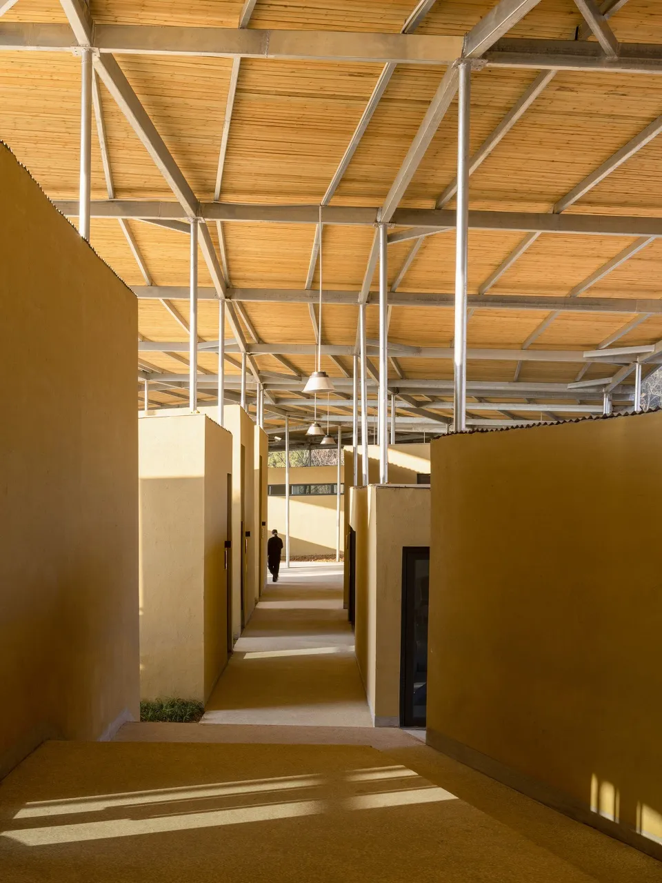 A long hallway with wood accents, two people walking, and a calm atmosphere