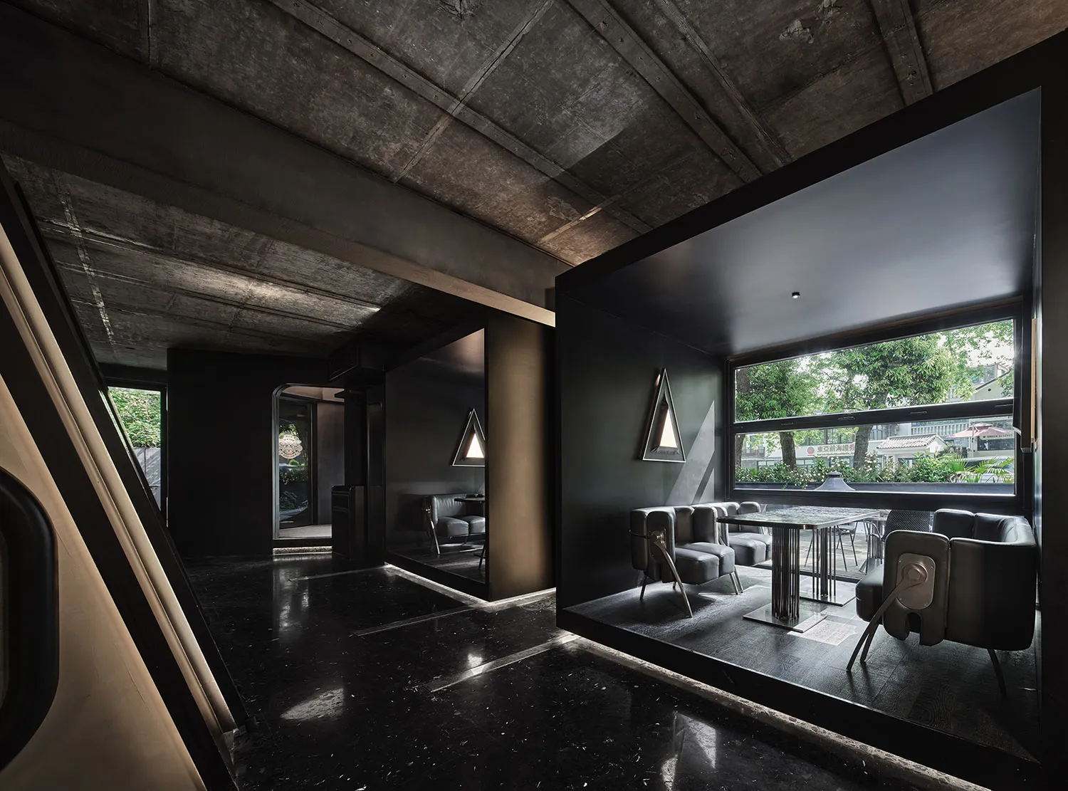 Modern open-plan living space with a black and white color scheme, featuring a dining area, living room, and potted plants, with a sleek and contemporary feel