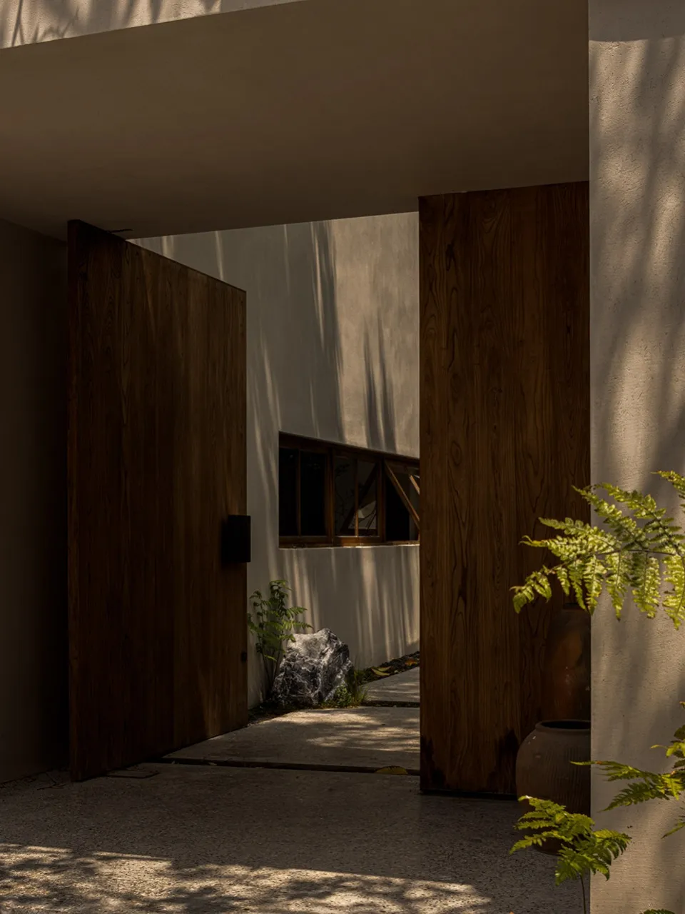Cozy living area with wooden entrance, two couches, and a potted plant, creating a warm and inviting atmosphere