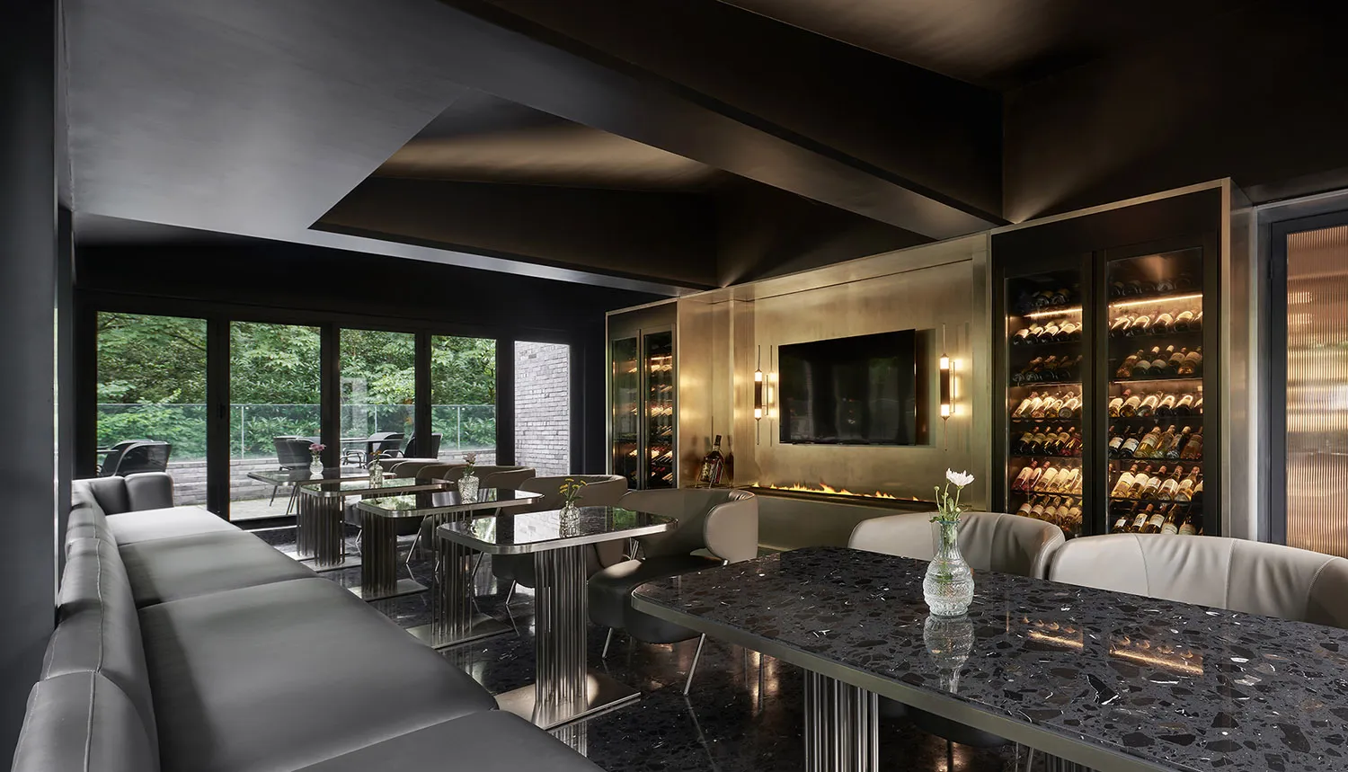 Sophisticated living space with a black marble table, chairs, and a mounted TV, surrounded by wine glasses