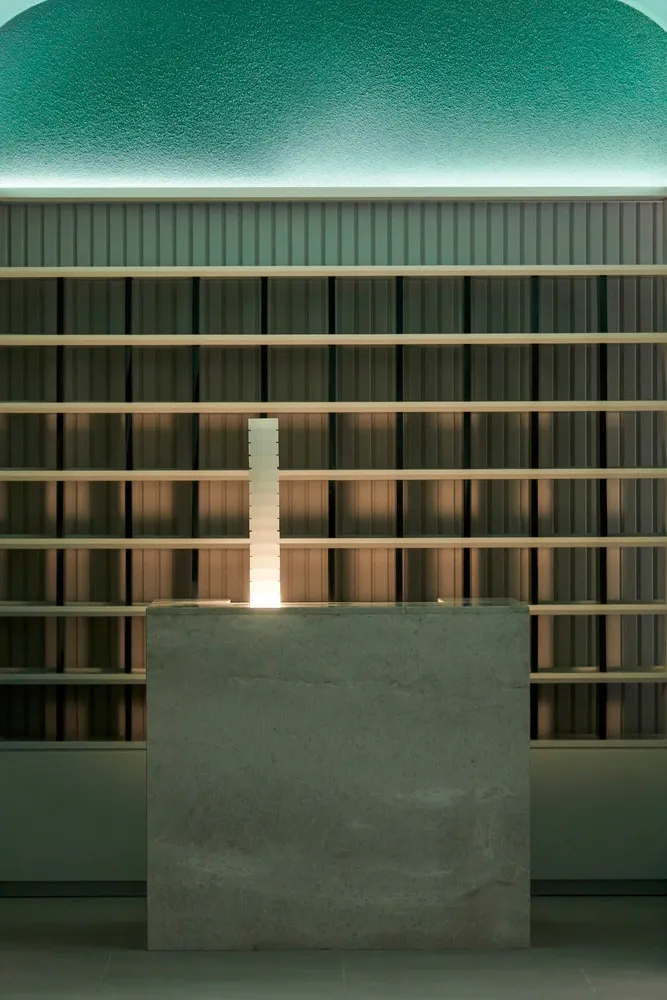 A stone table with a candle on top sits in front of a bookshelf filled with various books, creating a warm and inviting atmosphere for reading and relaxation