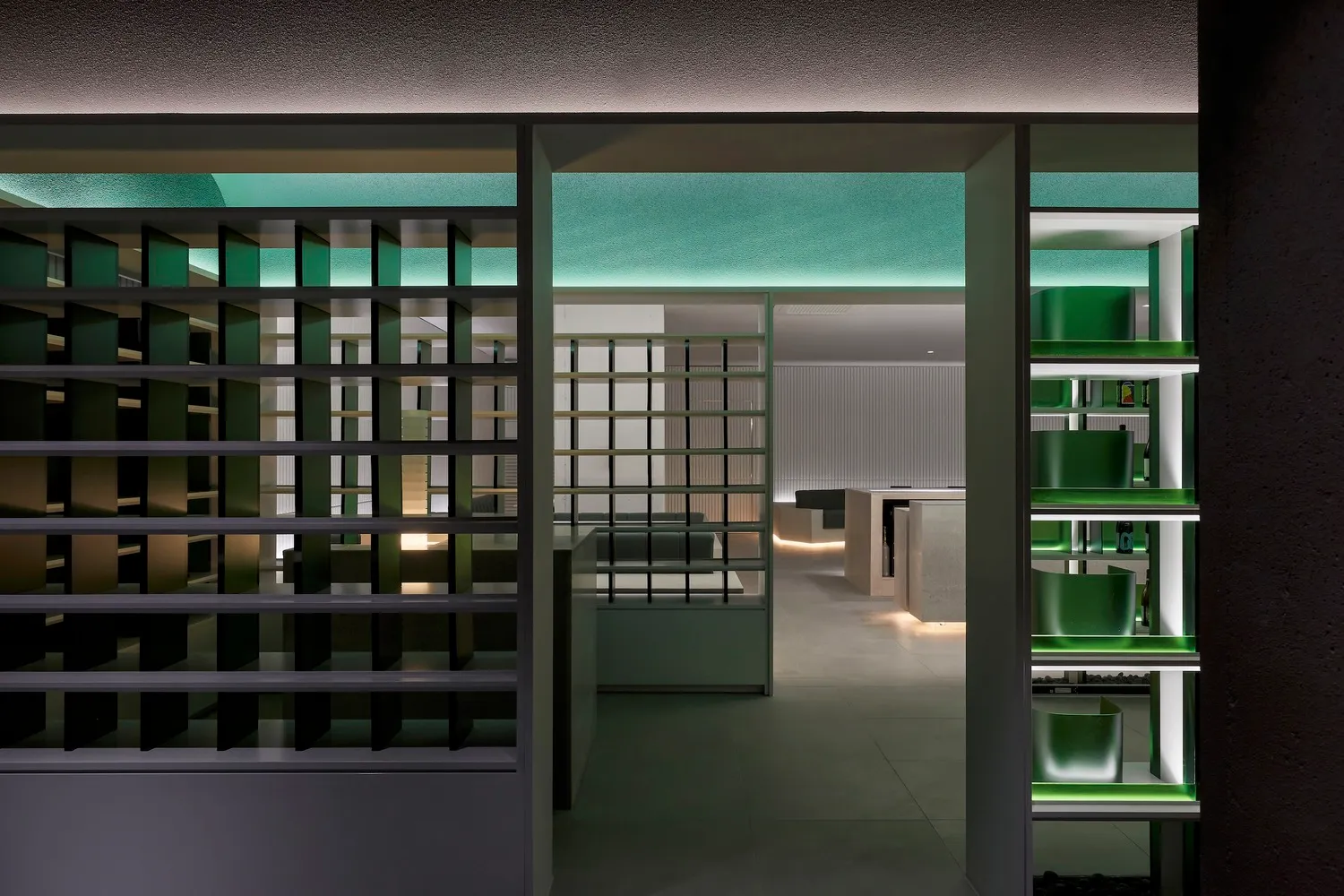 Modern kitchen with white walls, green accents, and a functional layout featuring a sink, oven, and refrigerator, with scattered bottles adding a personal touch