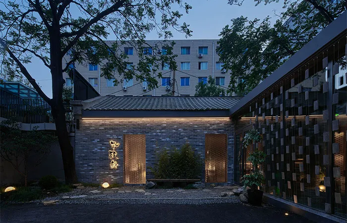 A courtyard surrounded by Asian-style buildings with a mix of traditional and modern elements, featuring a distinctive roof design and potted plants