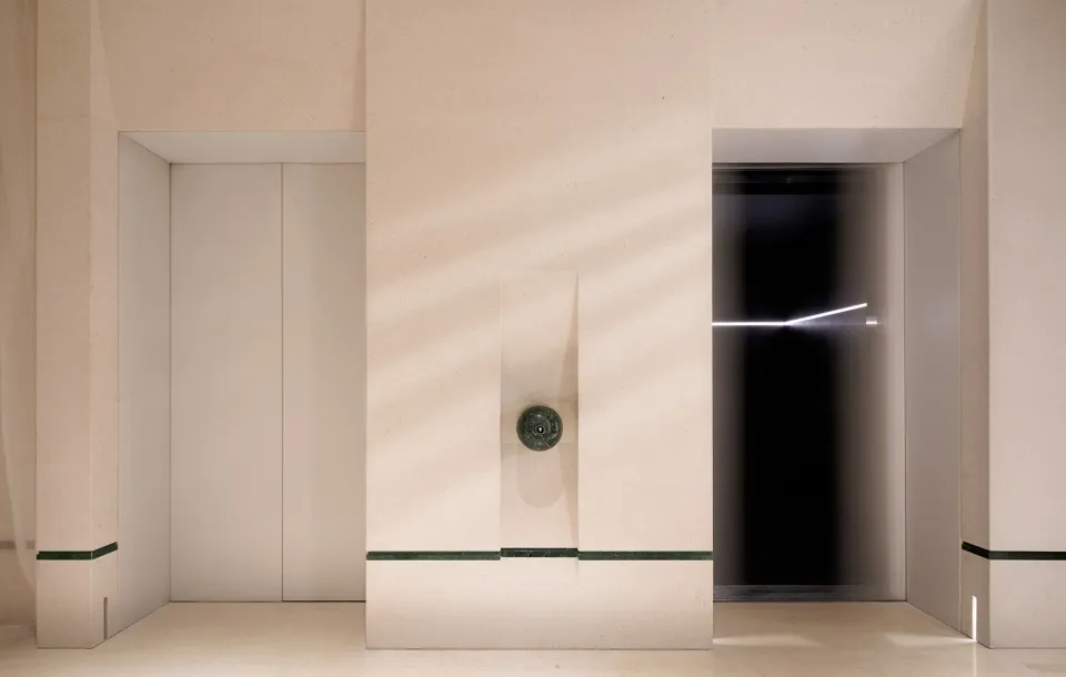 Classic hallway with a stone clock on the wall, a doorway leading to another room, and a timeless design