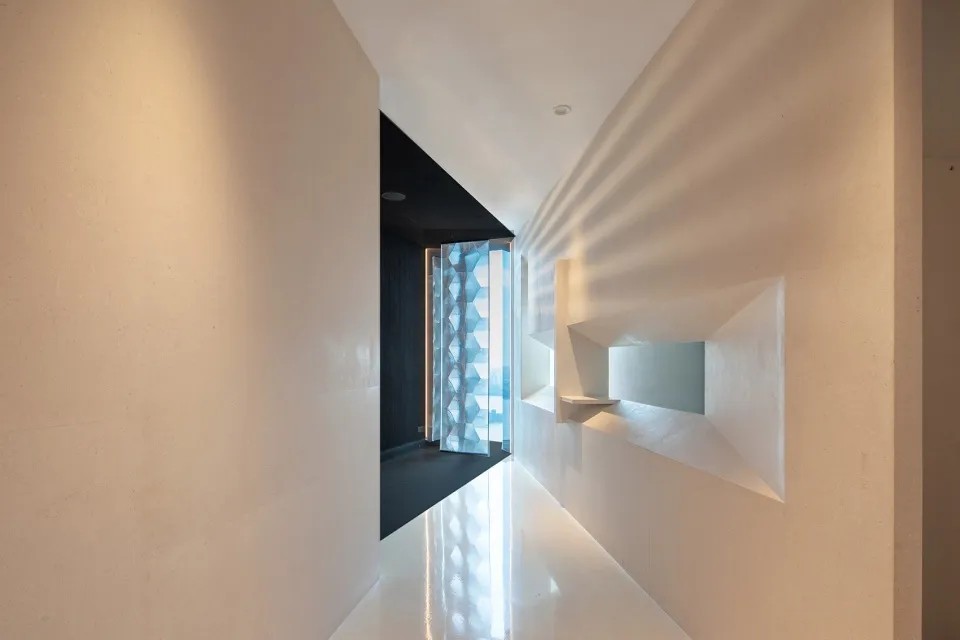 A bright and modern hallway with white walls and floors, featuring two doors and clean lines