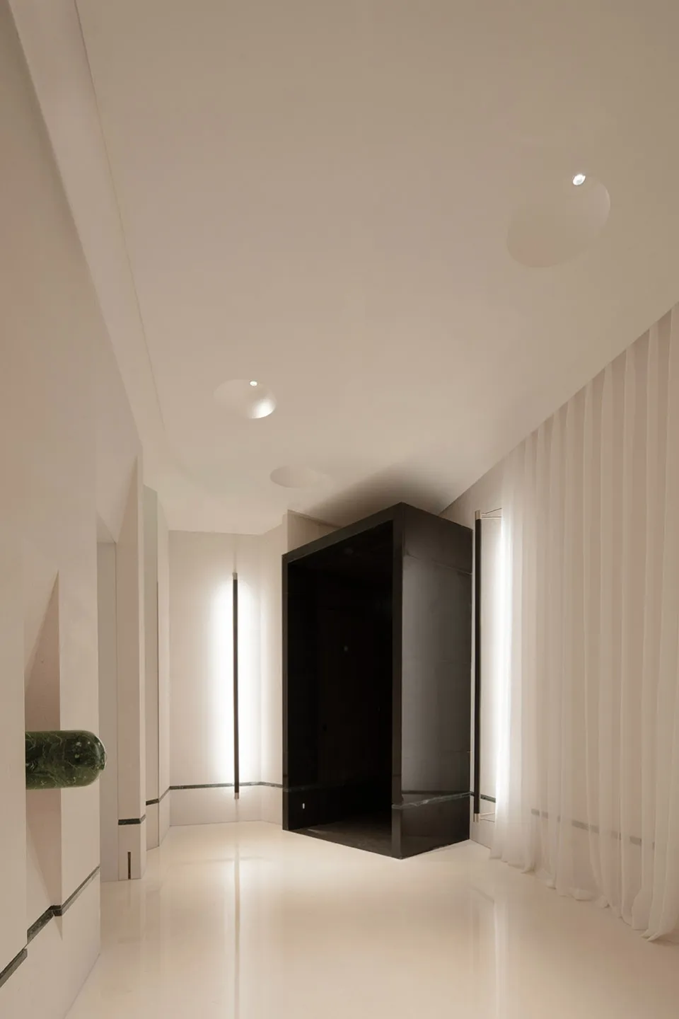 A clean and modern hallway with white walls and floors, lit by overhead lights, creating a calm and quiet atmosphere