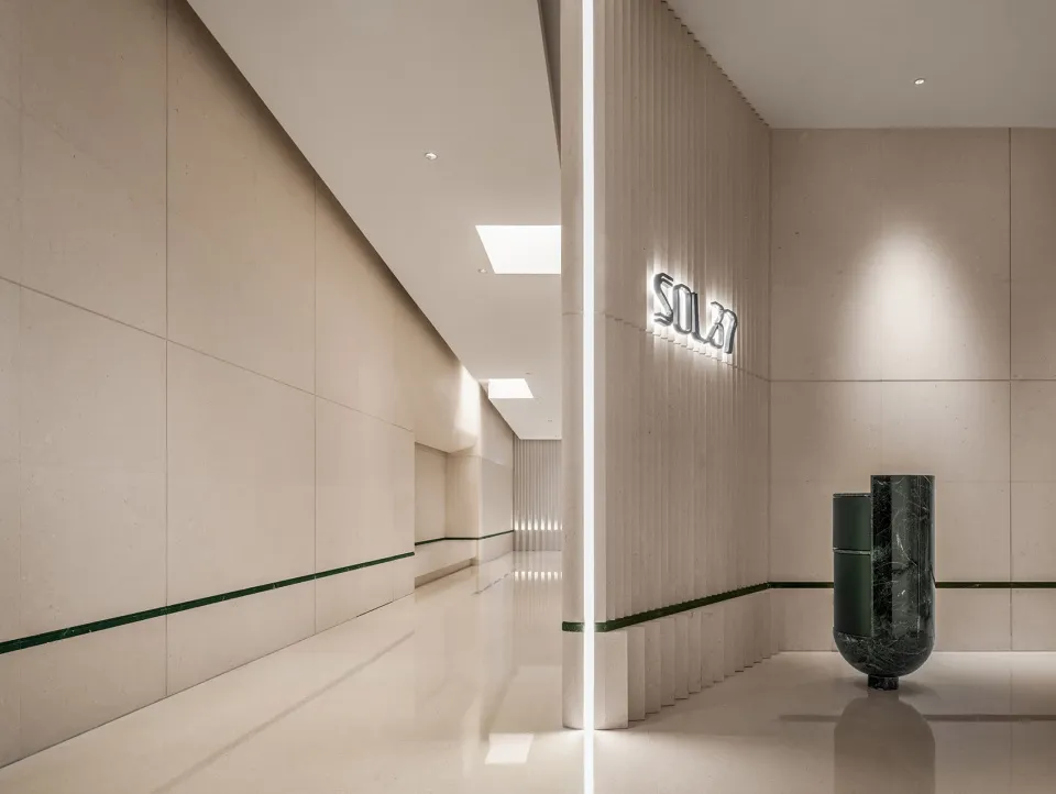 A calm and inviting hotel hallway with white marble flooring, two large vases, and a focus on aesthetics