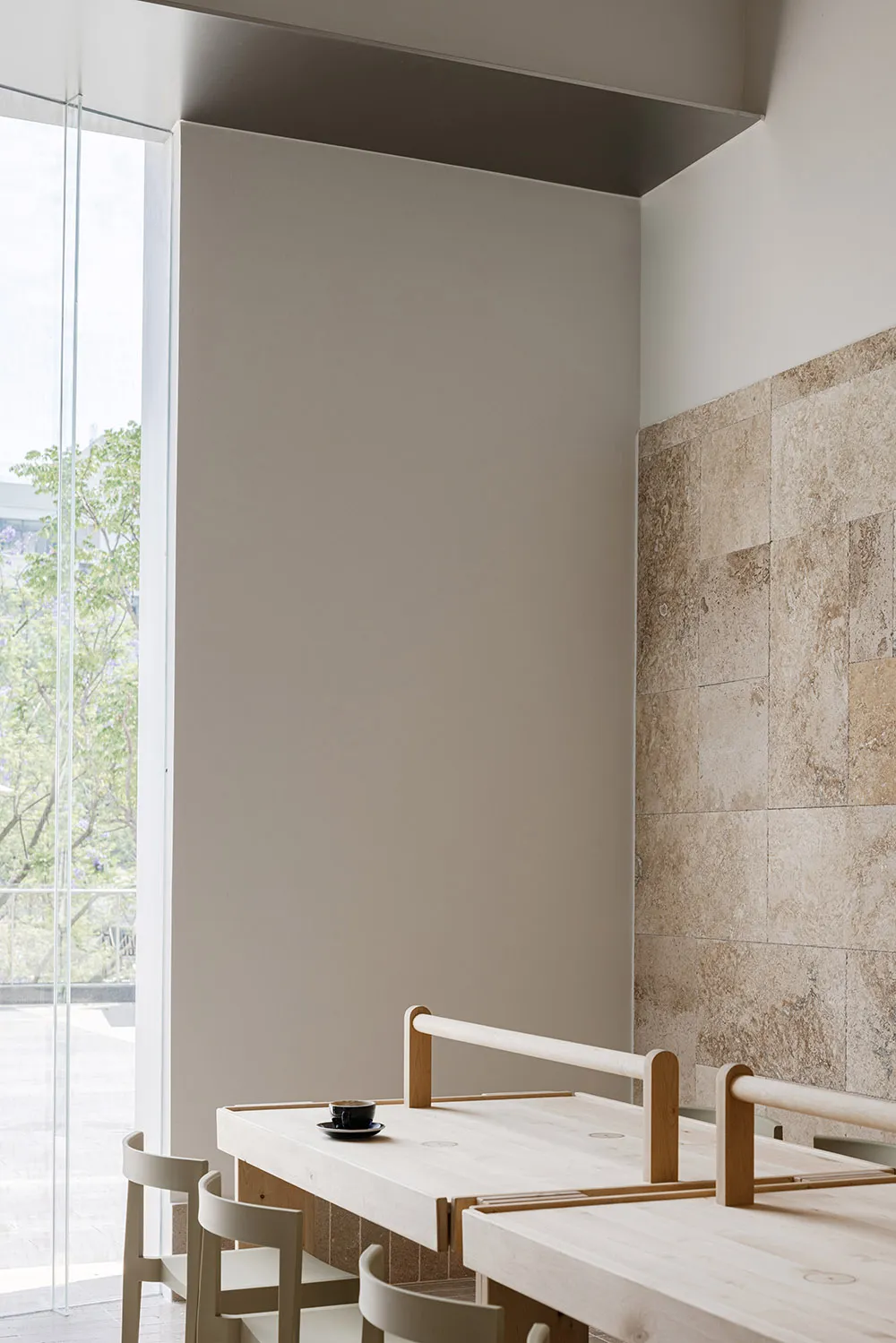 Empty bathroom with a white wall and beige tiles on the floor, featuring two wooden benches and a clean, minimalistic atmosphere