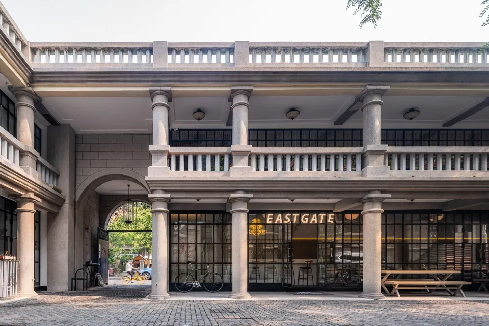 一座石材建築擁有大型拱門通往中庭，庭院內停放自行車靠近長椅，周圍環繞寧靜而溫馨的氛圍