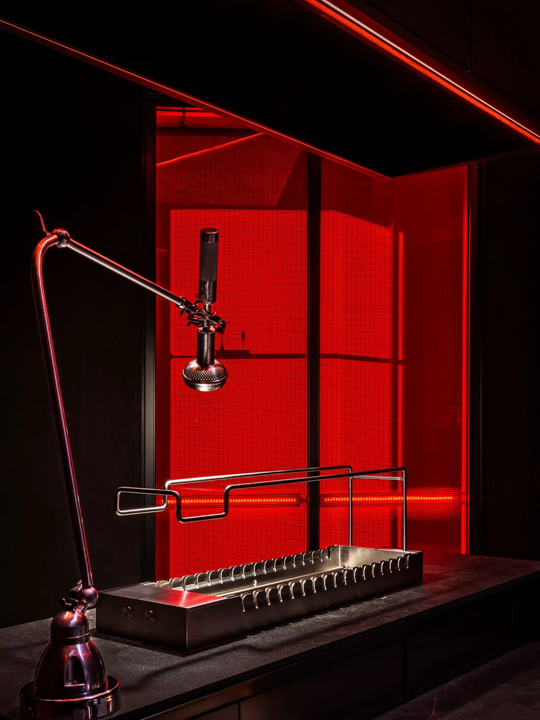 Modern kitchen with red walls, a metal sink with multiple faucets, and sleek design elements