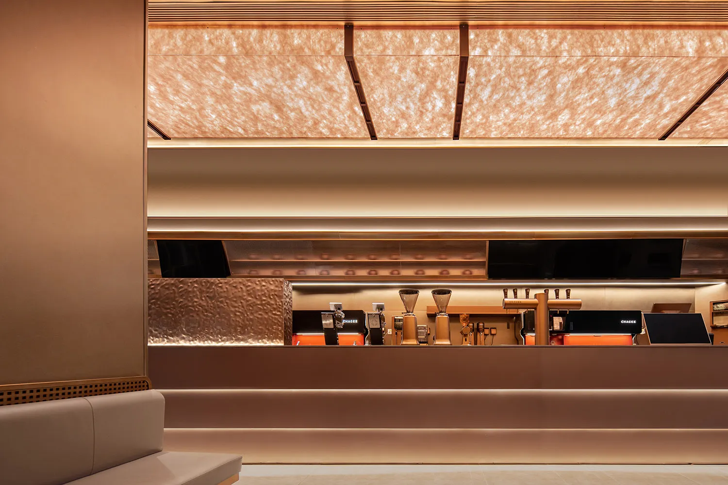 Modern bar with a counter, TV screens, and a warm atmosphere