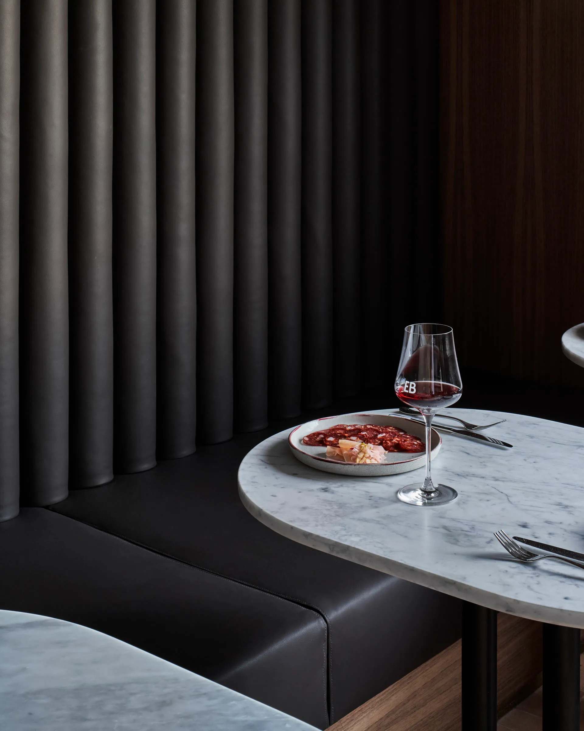 A single-occupant dining setup in a cozy restaurant with a wooden table, wine glass, and plate of food