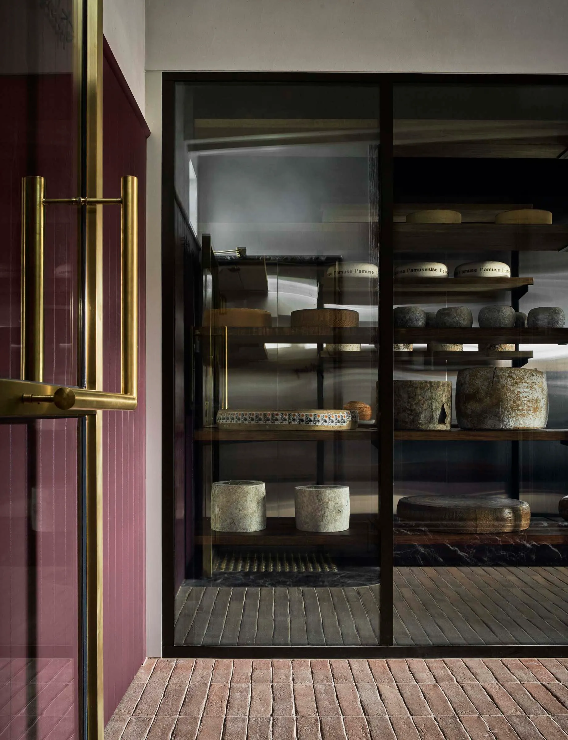 A well-organized cheese shop with a glass display case showcasing a variety of cheeses in different shapes, sizes, and colors