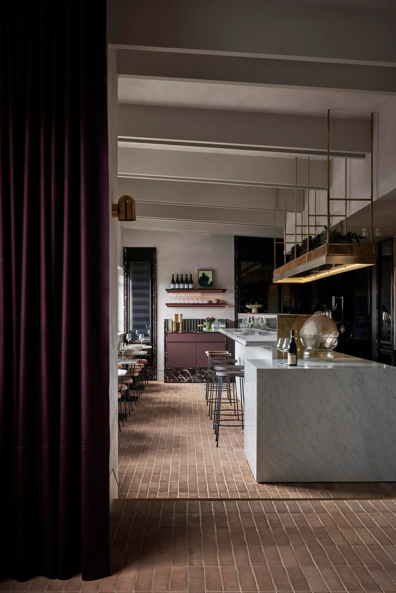 Elegant restaurant interior with marble countertops, a wine rack, and wooden accents, featuring a comfortable dining area and kitchenette