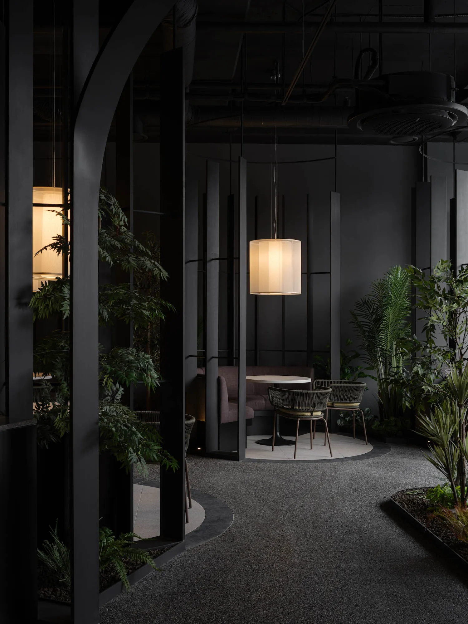 A modern living space with a dining table surrounded by chairs, multiple potted plants, and a vase, creating a cozy and inviting atmosphere