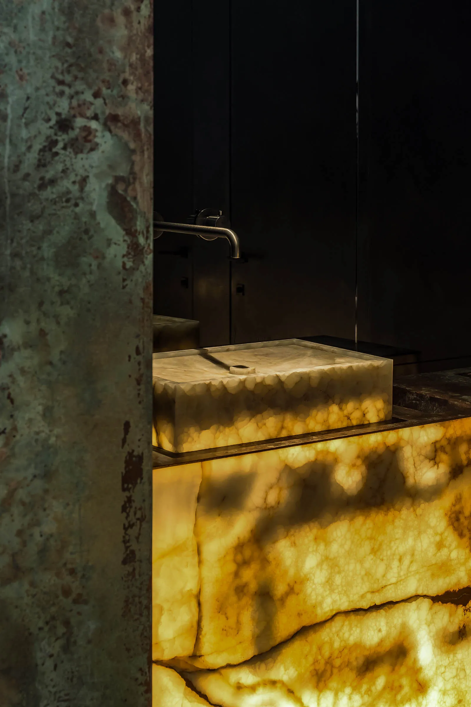 A vintage bathroom with a marble sink, a toilet, and a worn-down appearance