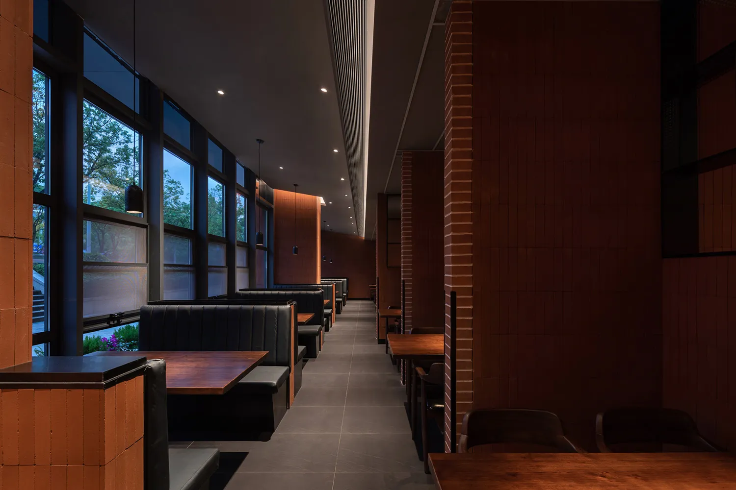 Warm and inviting restaurant interior with wooden floors, brick walls, and multiple dining tables and chairs