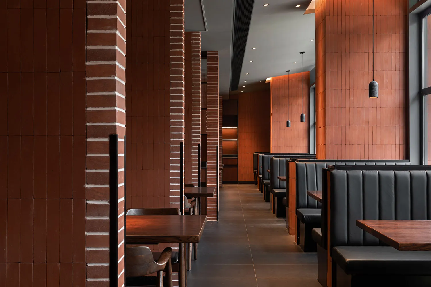 Warm restaurant interior with brick walls, wooden tables, and chairs, creating a comfortable atmosphere for diners