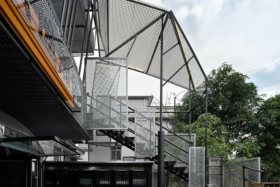 A modern building with multiple levels, metal structure, and stairs, showcasing a blend of architectural styles and materials