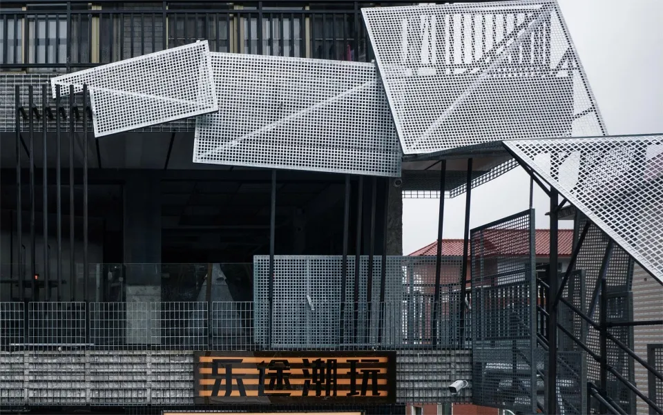 A modern Asian building with a metal facade, featuring multiple levels of balconies and a striking black and white color scheme
