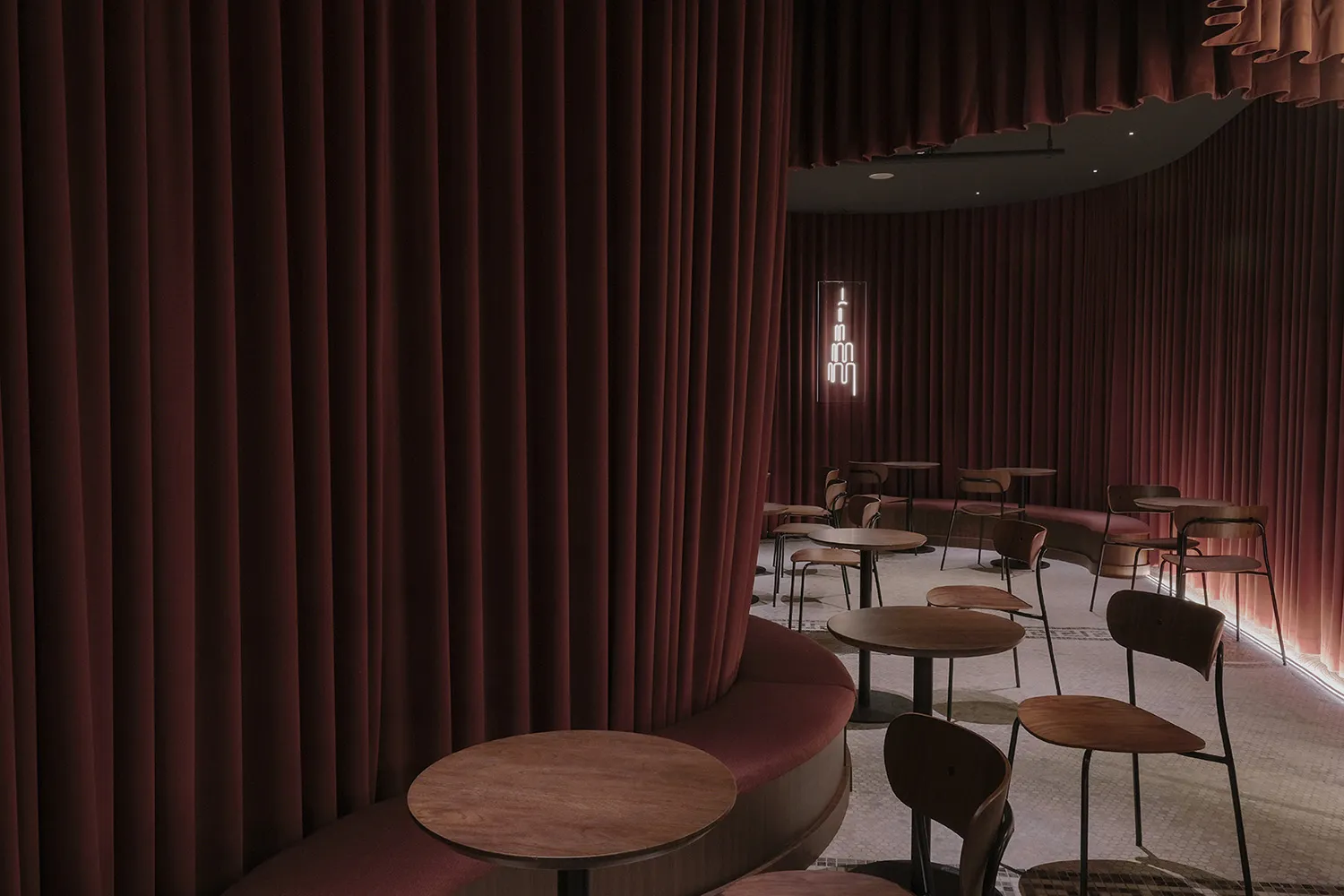 Cozy restaurant interior with red curtains, wooden tables, and comfortable seating