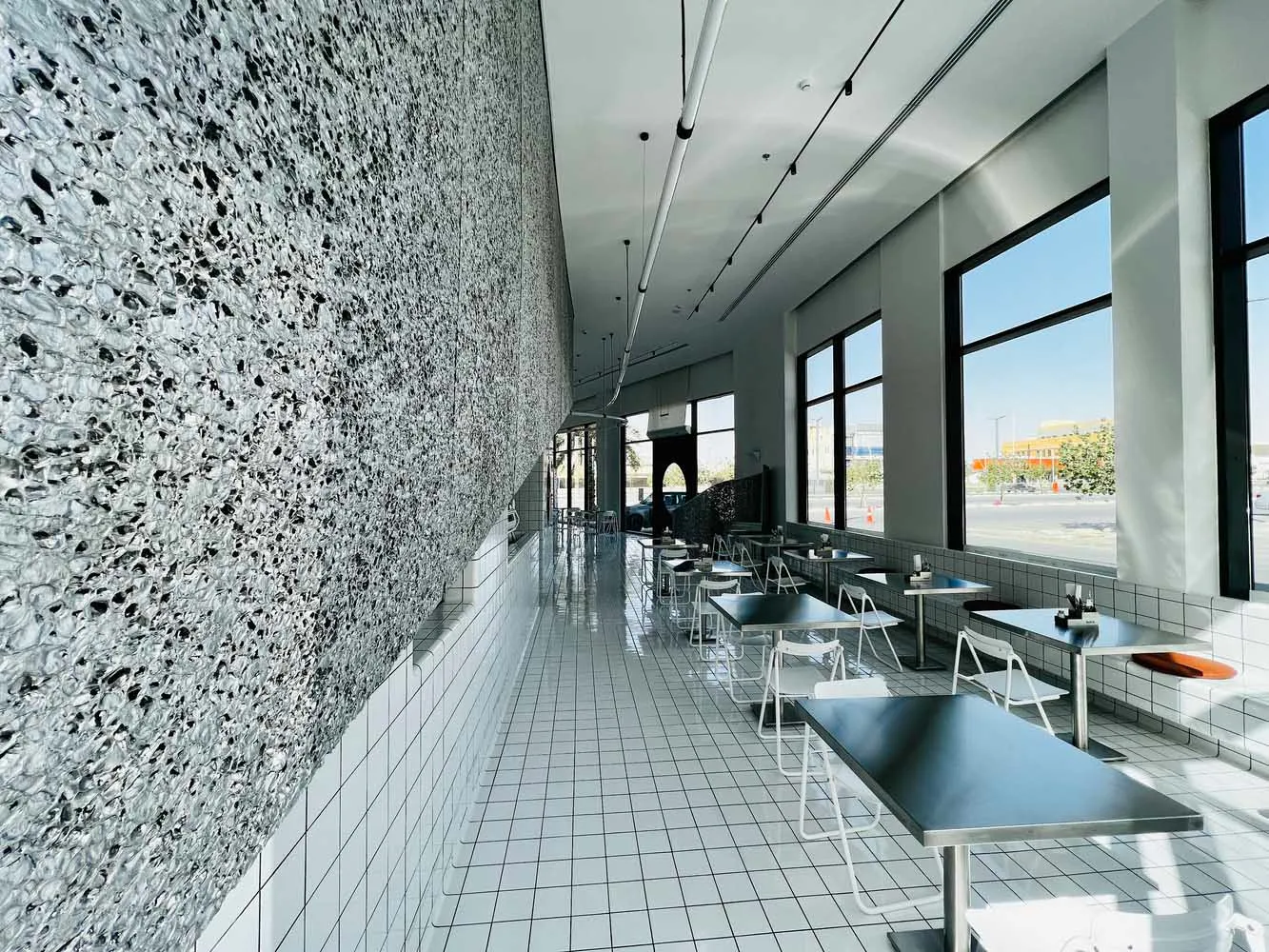 Empty modern restaurant with white tile floor, large window, and dining tables and chairs