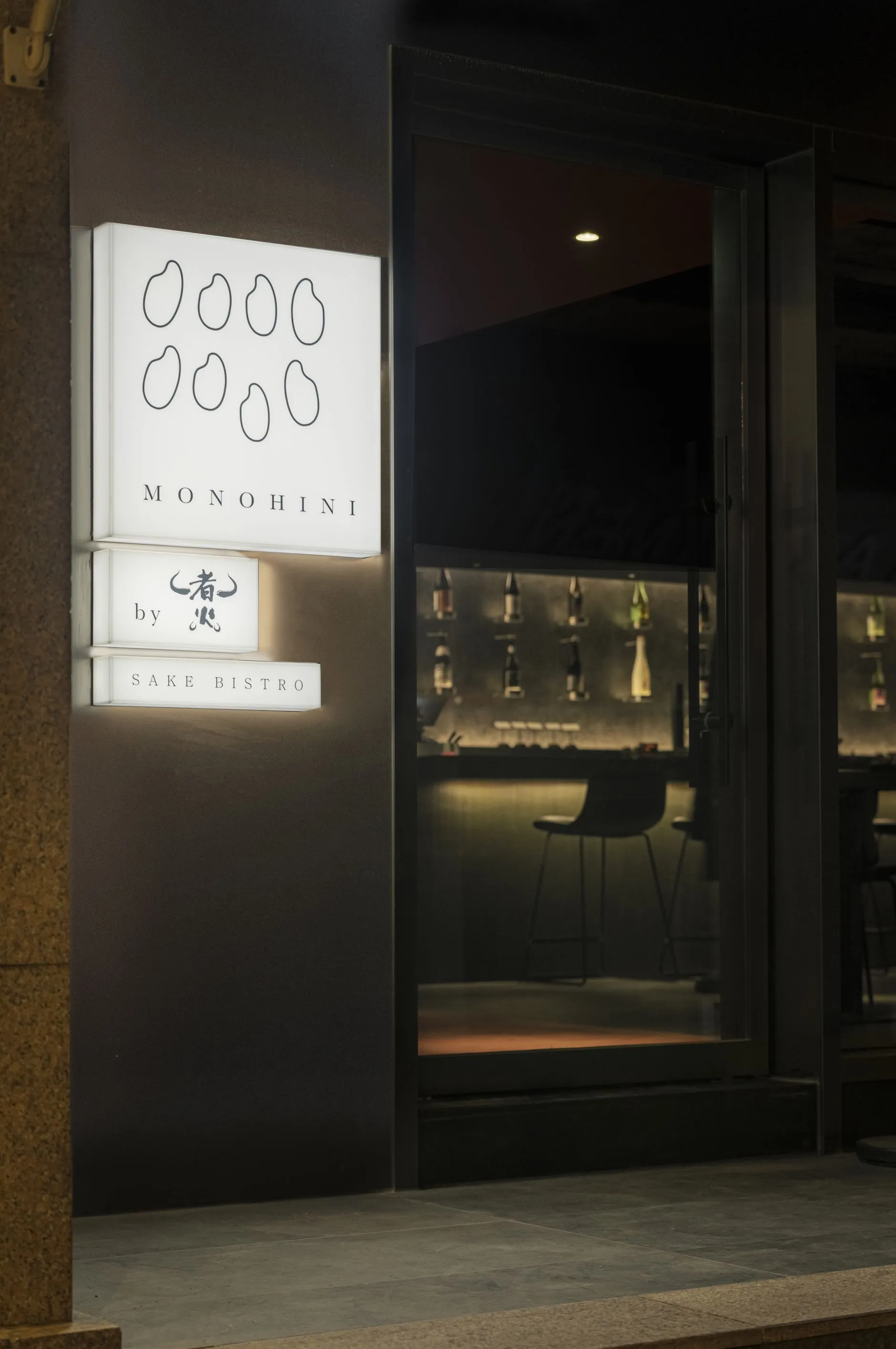 A restaurant interior with a wooden bar, bottles, and two chairs in a sophisticated atmosphere