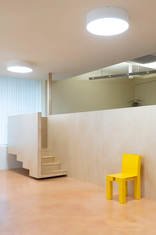 Cozy interior space with wooden walls and floors, a staircase, and a potted plant, creating a warm and inviting atmosphere