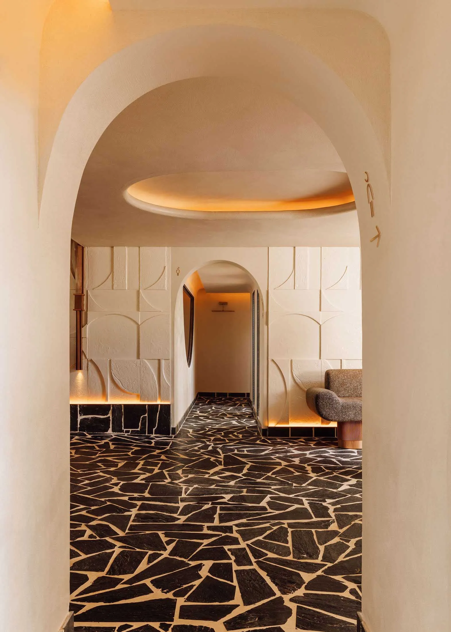 A modern hallway with a black and white checkered floor, featuring two benches and a chair, creating a stylish and inviting atmosphere