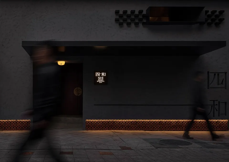 Gray modern building with a man walking towards the camera, another person walking away, and a third person in the background