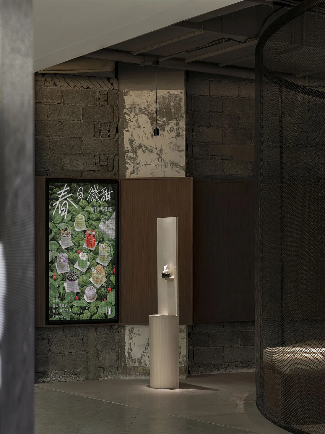 A modern interior space with a white pillar in the center, featuring two posters on the wall with a minimalist design