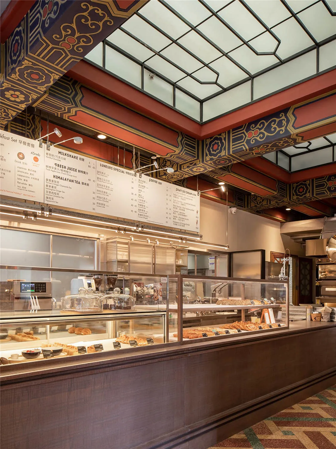 A modern bakery interior with glass cases displaying pastries, wood elements, and clean lines