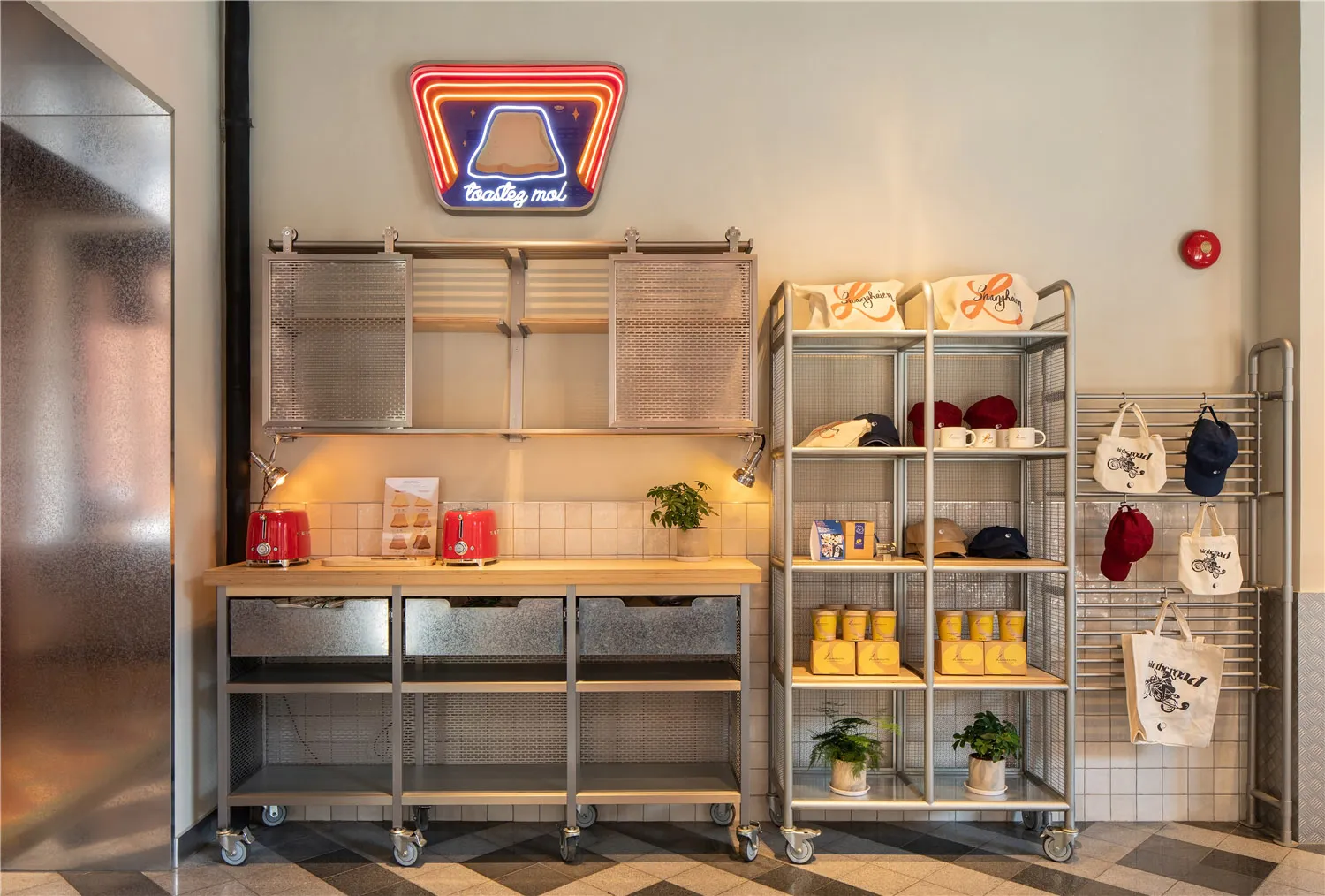 A casual restaurant or store interior with a counter featuring various items, cups, and bottles, accompanied by two potted plants