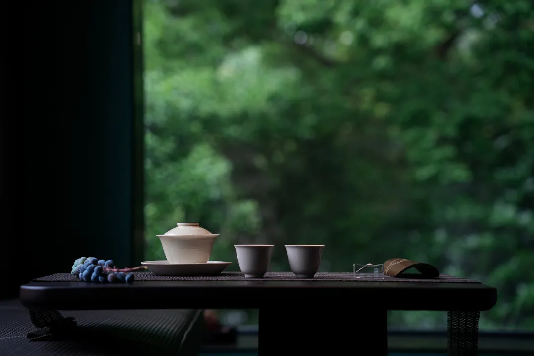 A wooden dining table with a tea set and a view through the window