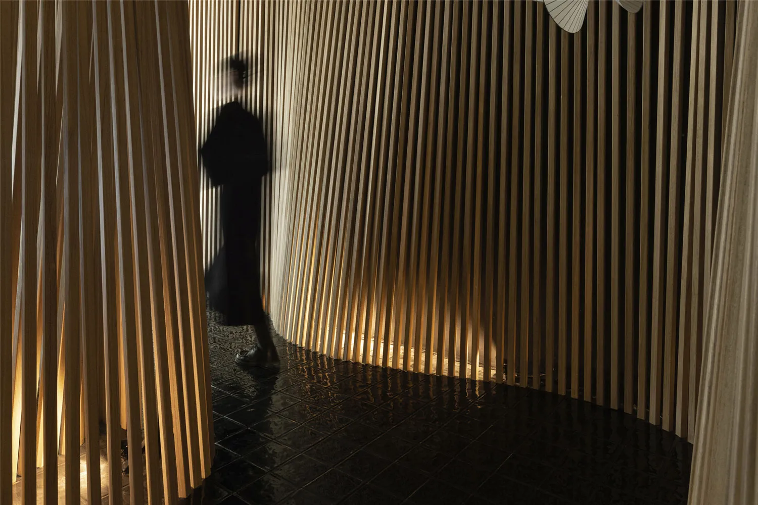 A woman walks down a calm and peaceful hallway with wooden walls and floors