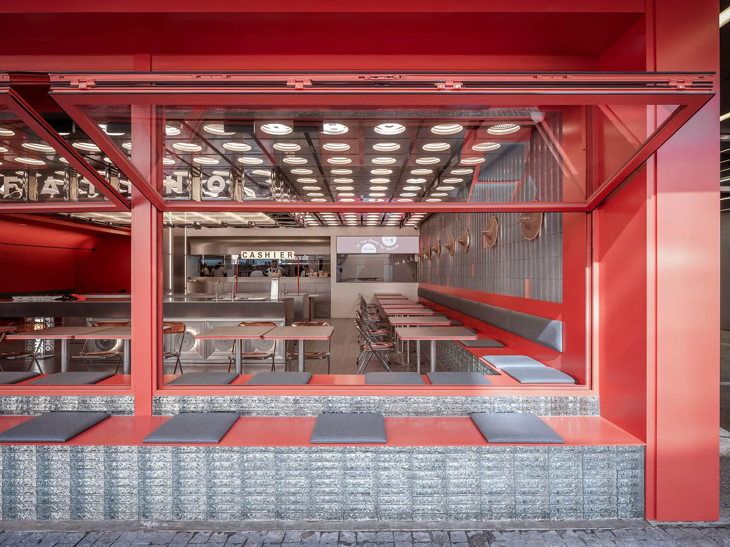A warm and inviting restaurant with red and white walls, dining tables, and comfortable seating, well-lit for a cozy ambiance