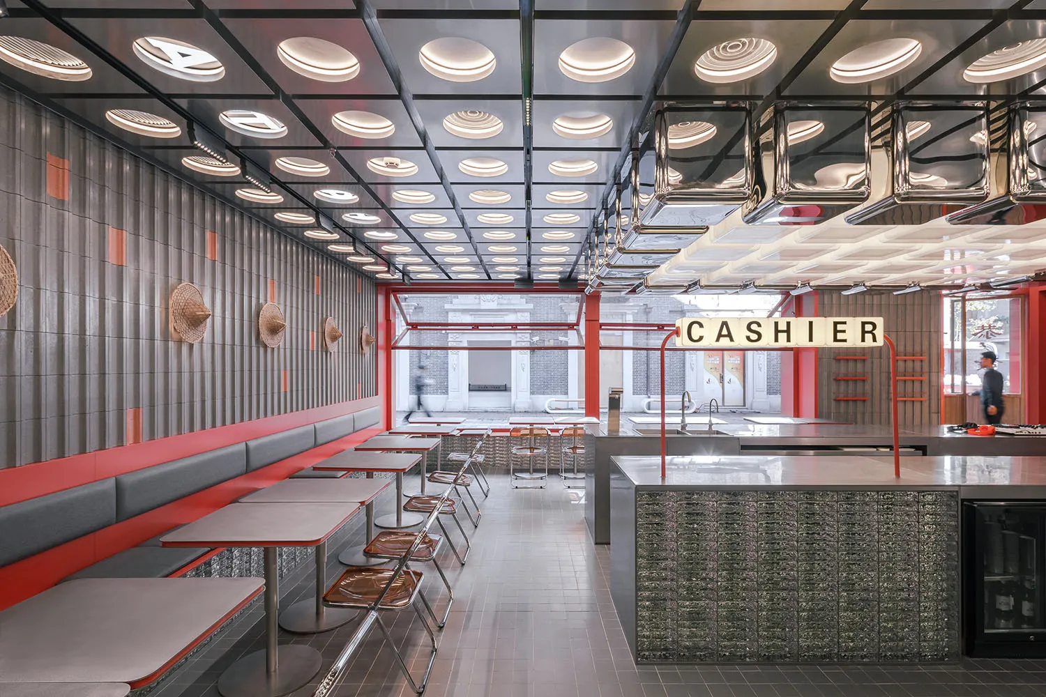 Casual restaurant interior with a counter and dining tables, featuring a cashier area and two people