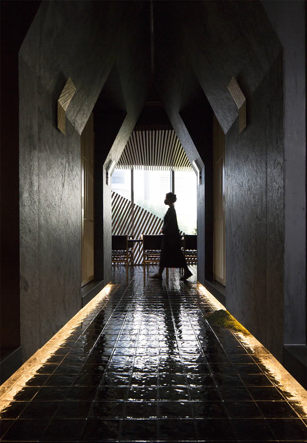 A calm and inviting hallway with a tiled floor, chairs, and a woman walking down the hall