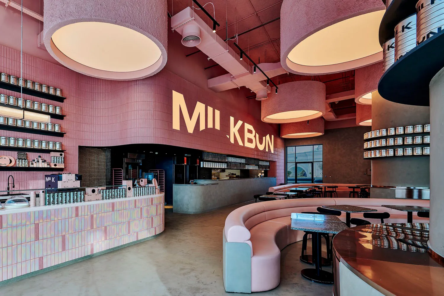 A modern restaurant interior with pink walls and ceiling, featuring dining tables and chairs in a comfortable and inviting atmosphere
