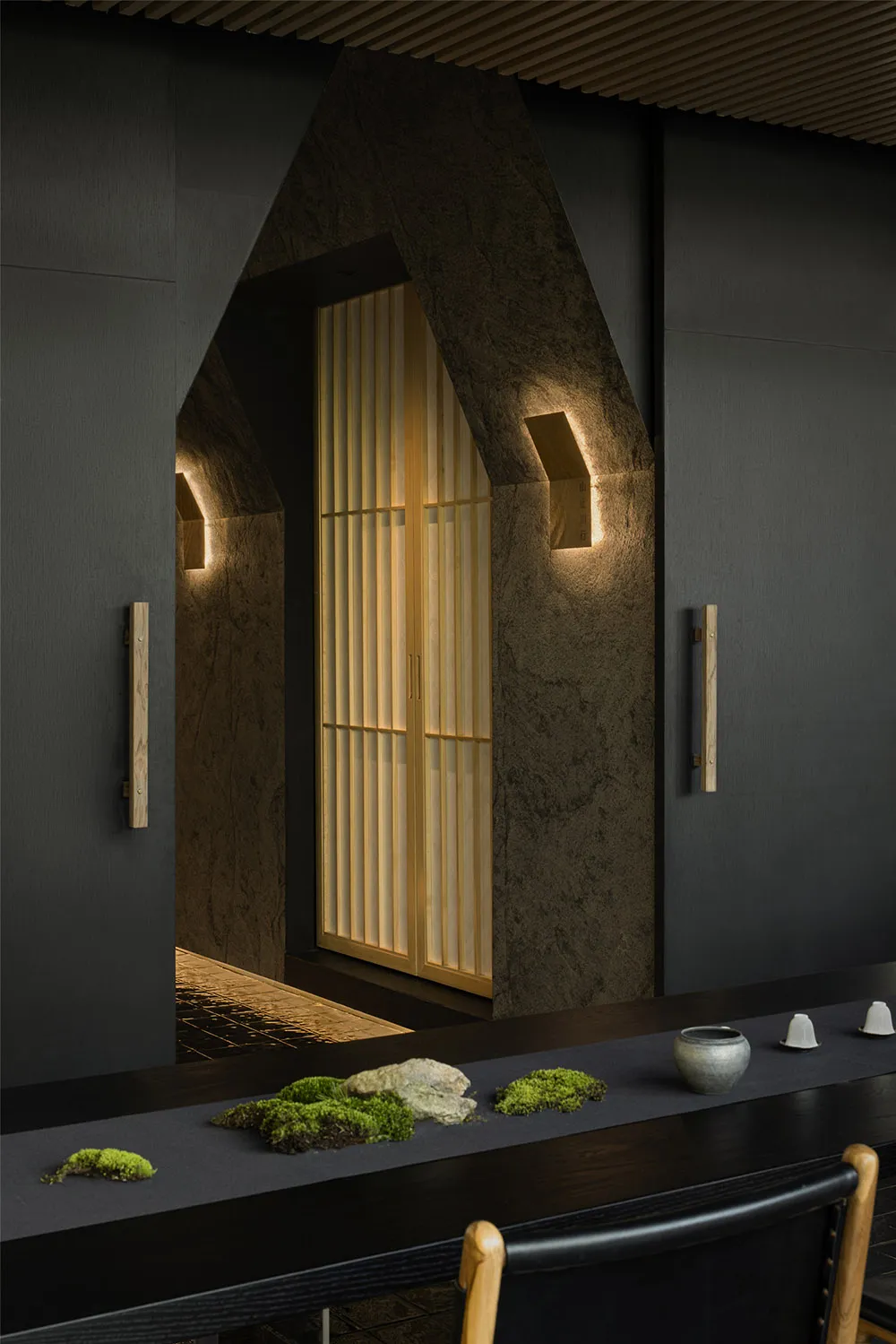 Dimly lit interior space with a wooden doorway, a glass window, and decorative bowls on a table